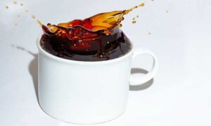 Dark Cup of Coffee Spilling Out of Coffee Cup.