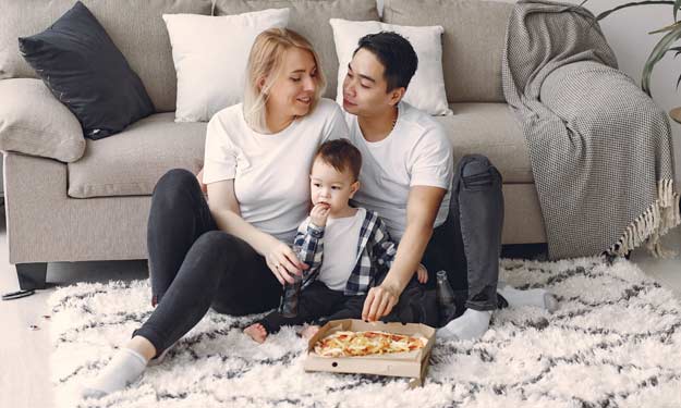 Young Couple Eating Pizza on Carpet. How to Remove Stains from Clothes and Carpets.