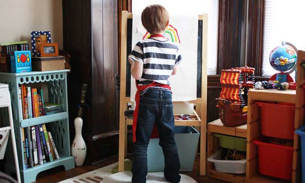 Young Boy Painting Picture in His Clean Room.