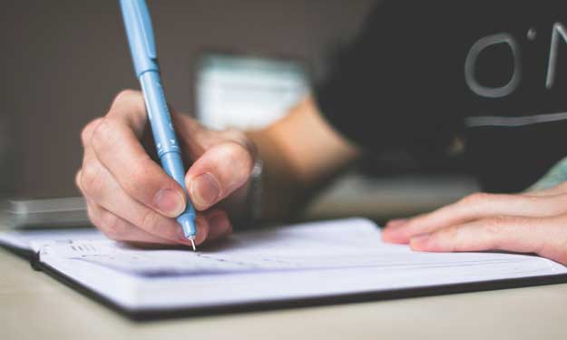 Man Writing Content on Piece of Paper.